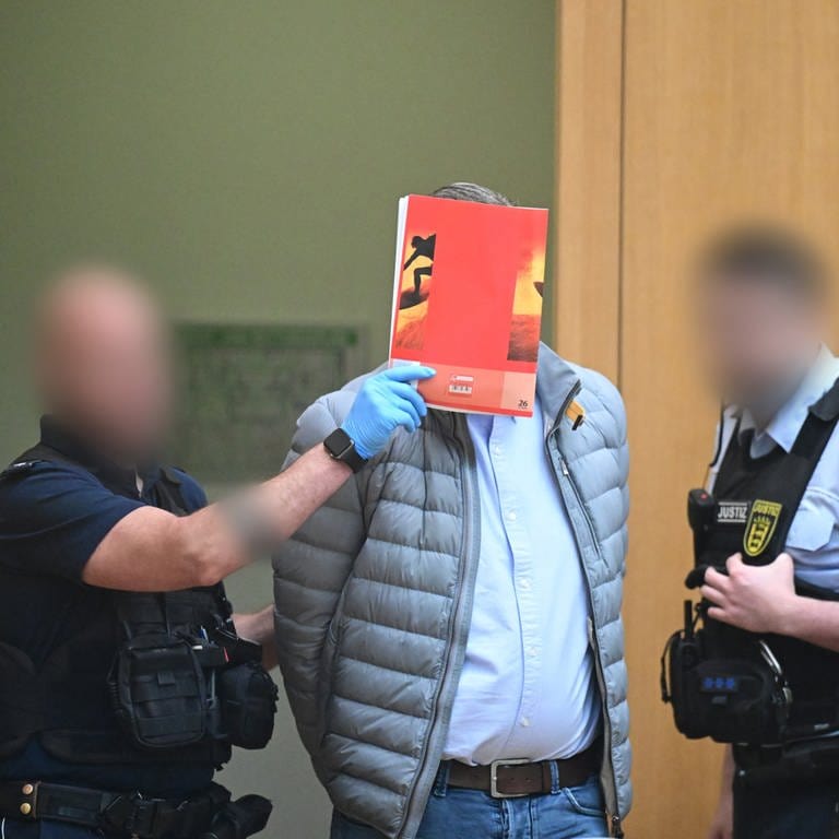 Ein Angeklagter wird in Stuttgart-Stammheim beim Beginn eines Prozesses um Reichsbürger in den Gerichtssaal geführt. (Foto: dpa Bildfunk, picture alliance/dpa/dpa-Pool | Bernd Weißbrod)